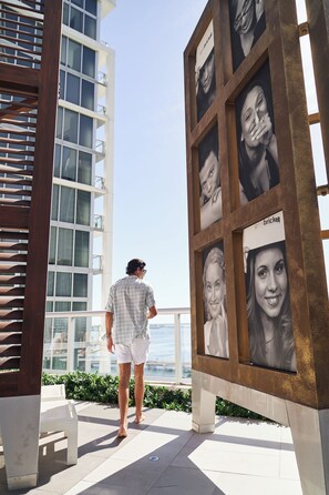 A man walking past a building with large framed portraits and a modern design.