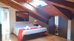 A bedroom with a sloped ceiling, a bed with a red blanket, a bedside lamp, and a mirror on the wall. - Hotel Alibì (Rimini)