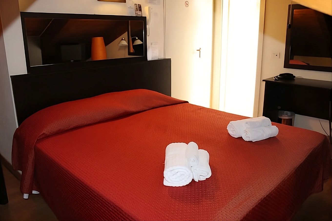 A hotel room with a bed, a TV, and a mirror.
