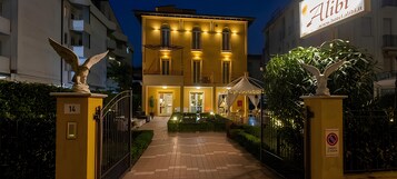 A hotel entrance with a gated driveway, a signboard, and a statue.