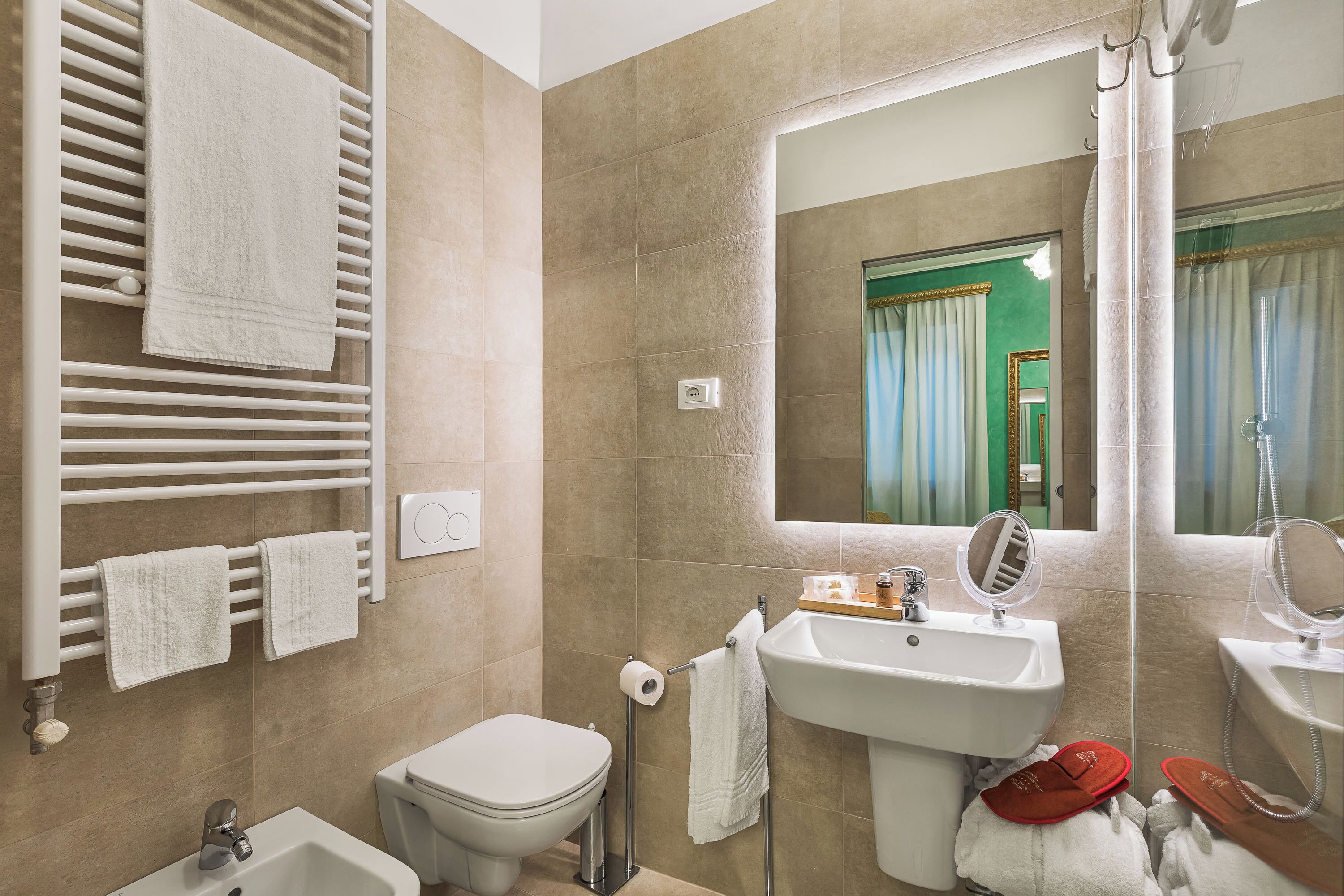 A bathroom with a toilet, bidet, sink, and mirror.