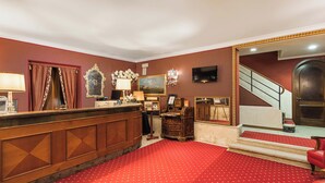 A hotel lobby with a reception desk, a staircase, and a red carpeted floor. - Hotel Ca' Alvise (Venice)