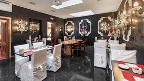 A dining area with round tables and chairs, chandeliers, and artwork on the walls. - Hotel Ca' Alvise (Venice)