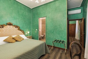 Una camera da letto con una parete verde, un letto con struttura in legno e una piccola sedia di legno.