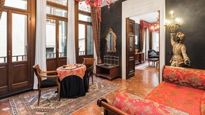 A room with a dining table set, a sofa, a chandelier, and a large mirror. - Hotel Ca' Alvise (Venice)