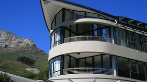 A modern building with large windows and a balcony, overlooking a mountainous landscape. - The Glen Apartments (Cape Town)