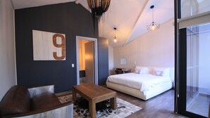 A modern bedroom with a large bed, a wooden coffee table, a sofa, and a wall-mounted number '9'. - The Glen Apartments (Cape Town)