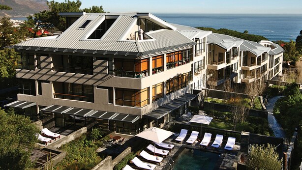 A modern multi-story hotel with a rooftop pool, outdoor seating, and a view of the ocean. - The Glen Apartments (Cape Town)