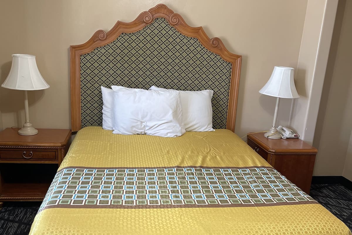 Quarto de hotel com uma cama grande, duas mesas de cabeceira e uma cabeceira estampada.