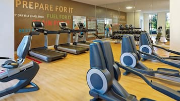 A gym with treadmills, elliptical machines, and dumbbells.