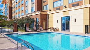 Un hotel con piscina, sillones de descanso y fachada de ladrillo.
