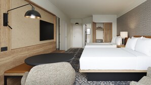 Habitación de hotel con dos camas, un escritorio, una silla, un televisor y una lámpara.