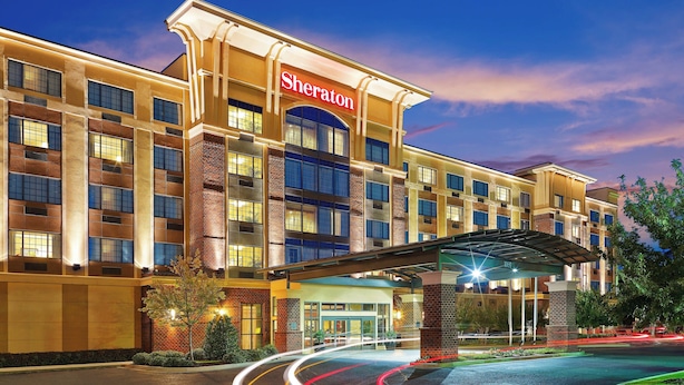 Un hotel Sheraton con fachada moderna, varios pisos y entrada cubierta.