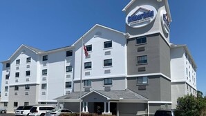 A Suburban Extended Stay Hotel with a modern design, multiple floors, and a prominent entrance with a flag. - Suburban Studios near Panama City Beach (Panama City)