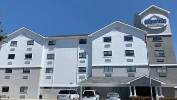 A suburban extended stay hotel with a modern design, featuring multiple parking spaces and a clear sky.