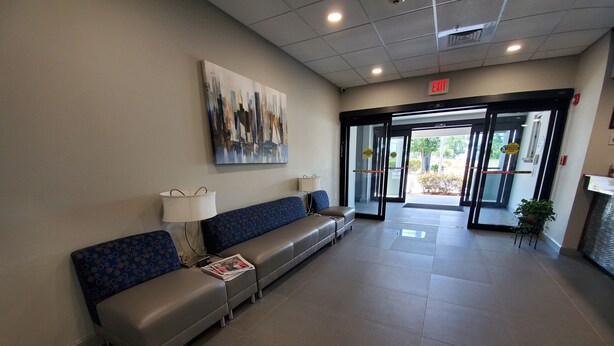 A reception area with a sofa, a lamp, and a painting on the wall. - Suburban Studios near Panama City Beach (Panama City)