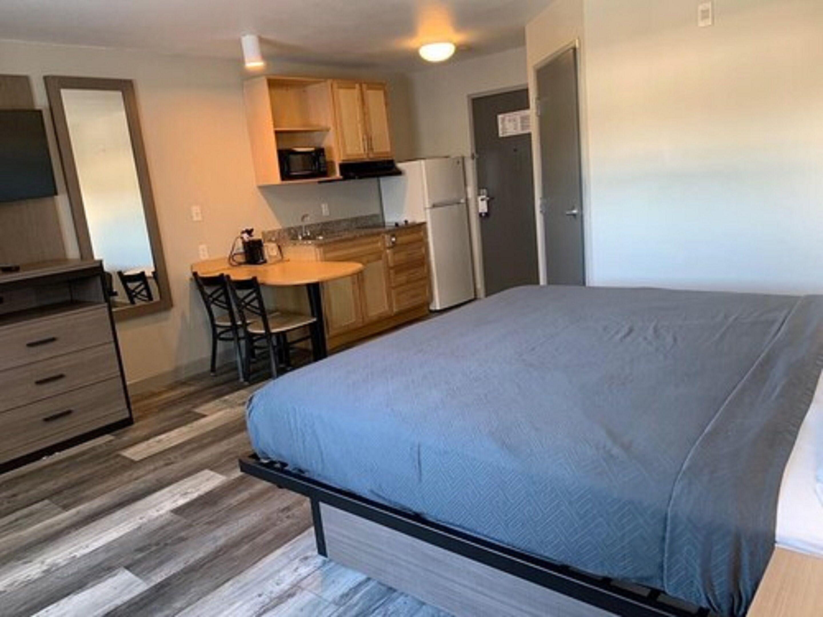 A compact room with a bed, a small kitchenette, and a desk.
