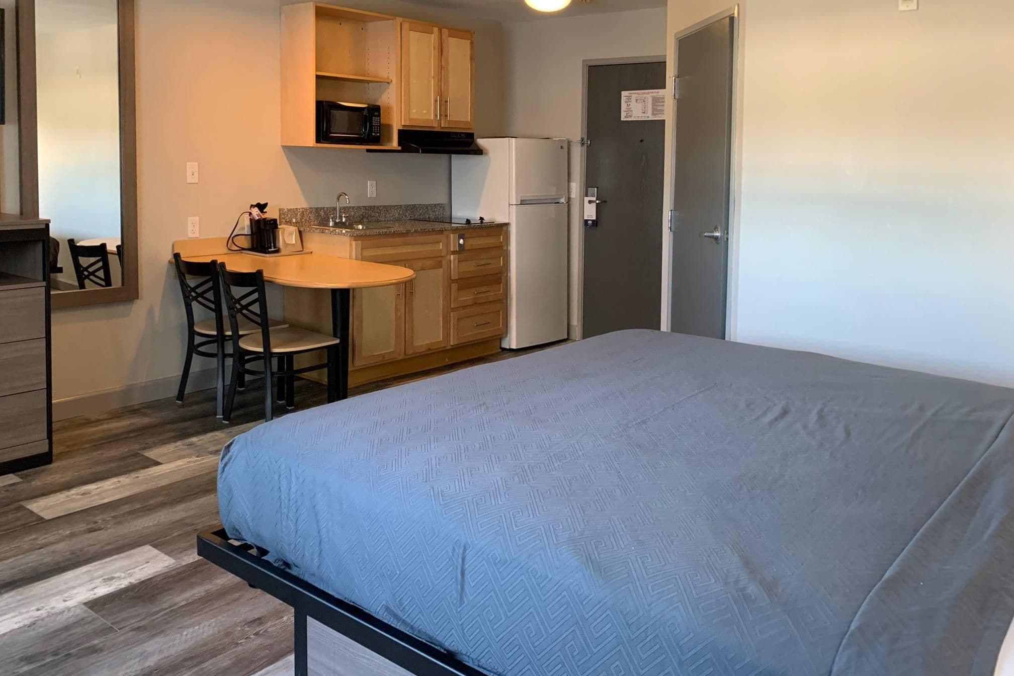A compact room with a bed, a kitchenette, and a small dining area.