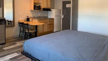 A compact room with a bed, a kitchenette, and a small dining area.