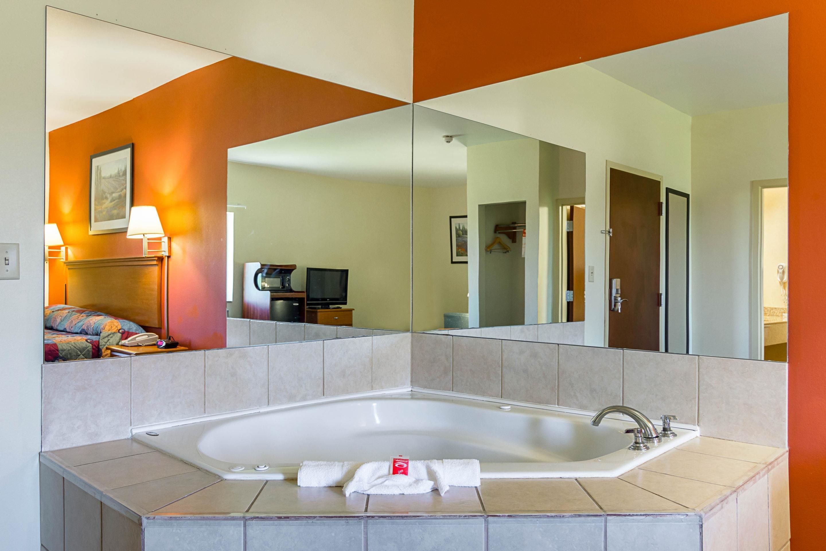 Ein modernes Badezimmer mit einer großen Badewanne, einem Spiegel und einer Duschkabine.