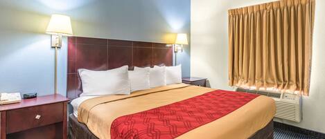 Habitación de hotel con una cama grande, dos mesitas de noche, una lámpara de pared, una ventana con cortinas y un equipo de aire acondicionado.