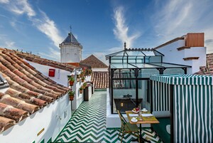 A rooftop terrace with a green and white chevron-patterned floor, a glass-enclosed dining area, and a traditional tiled roof.