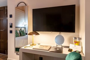 Ein Hotelzimmer mit einem Bett, einem Schreibtisch mit Lampe, einem Flachbildfernseher und einer Minibar.