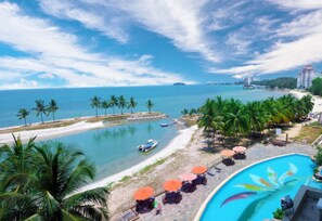 Un complexe hôtelier doté d’une piscine, d’une plage et offrant une vue sur l’océan.