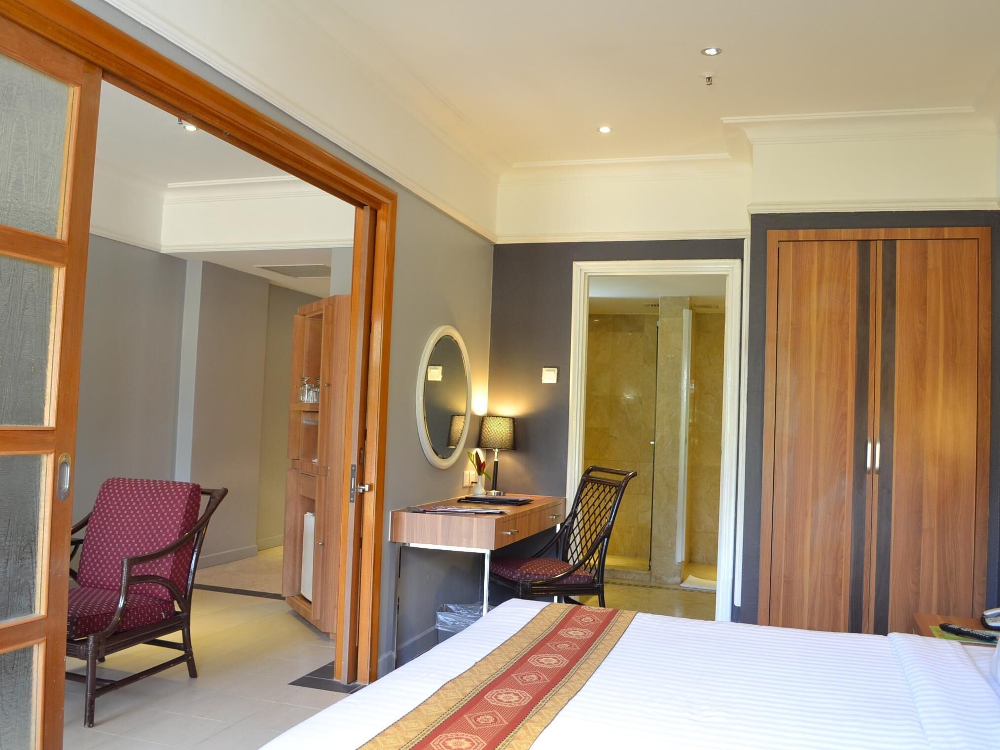 Een hotelkamer met een bed, een bureau, een stoel, een spiegel en een kledingkast.