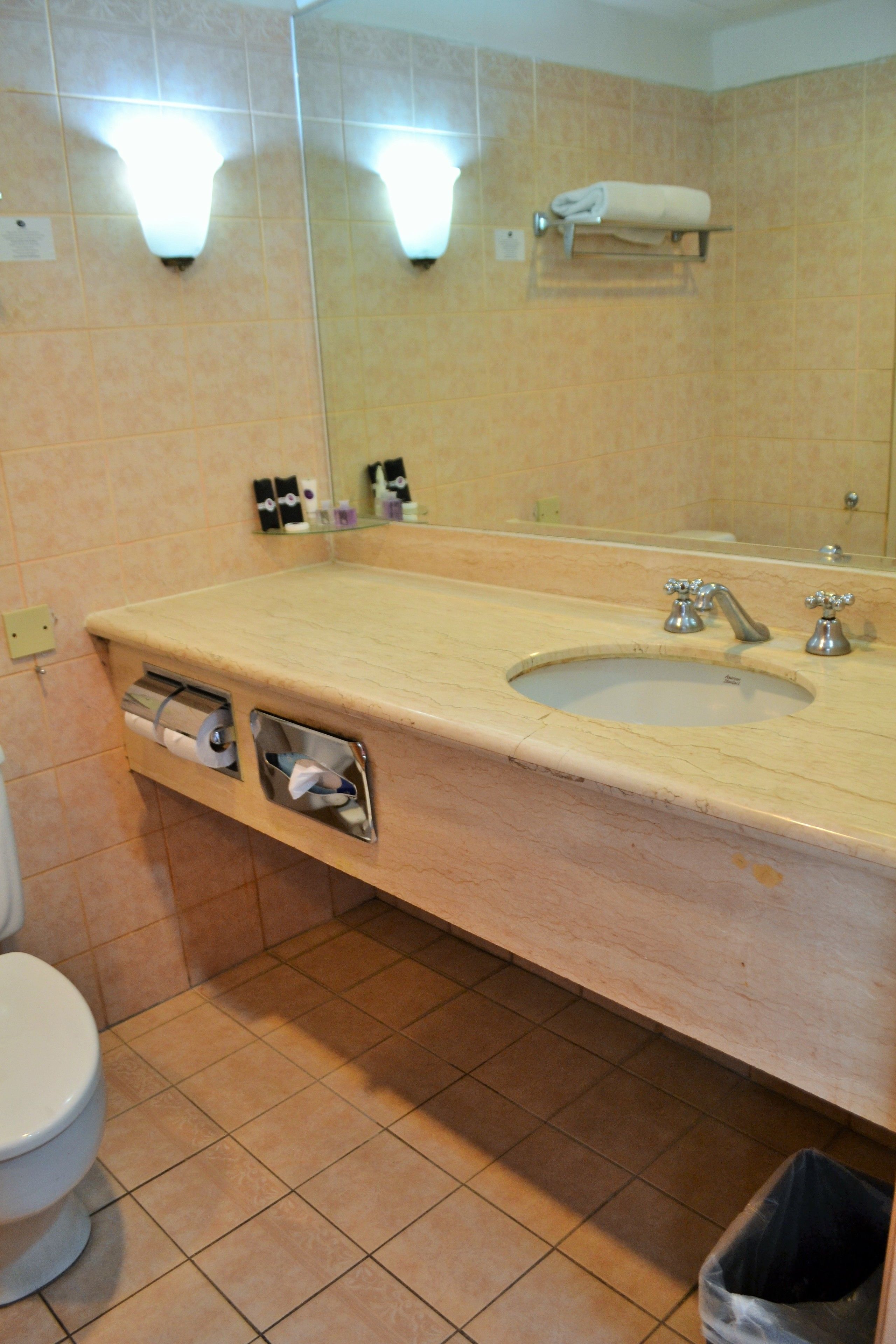A bathroom with a sink, mirror, towel rack, and toilet.