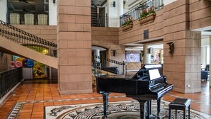 A grand piano in a spacious lobby with a patterned floor, a staircase, and a balcony with flowers. - Corus Paradise Resort Port Dickson (Port Dickson)