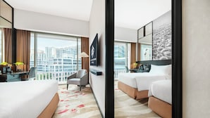 Habitación de hotel con un ventanal grande, un escritorio con lámpara, una cama y una silla.