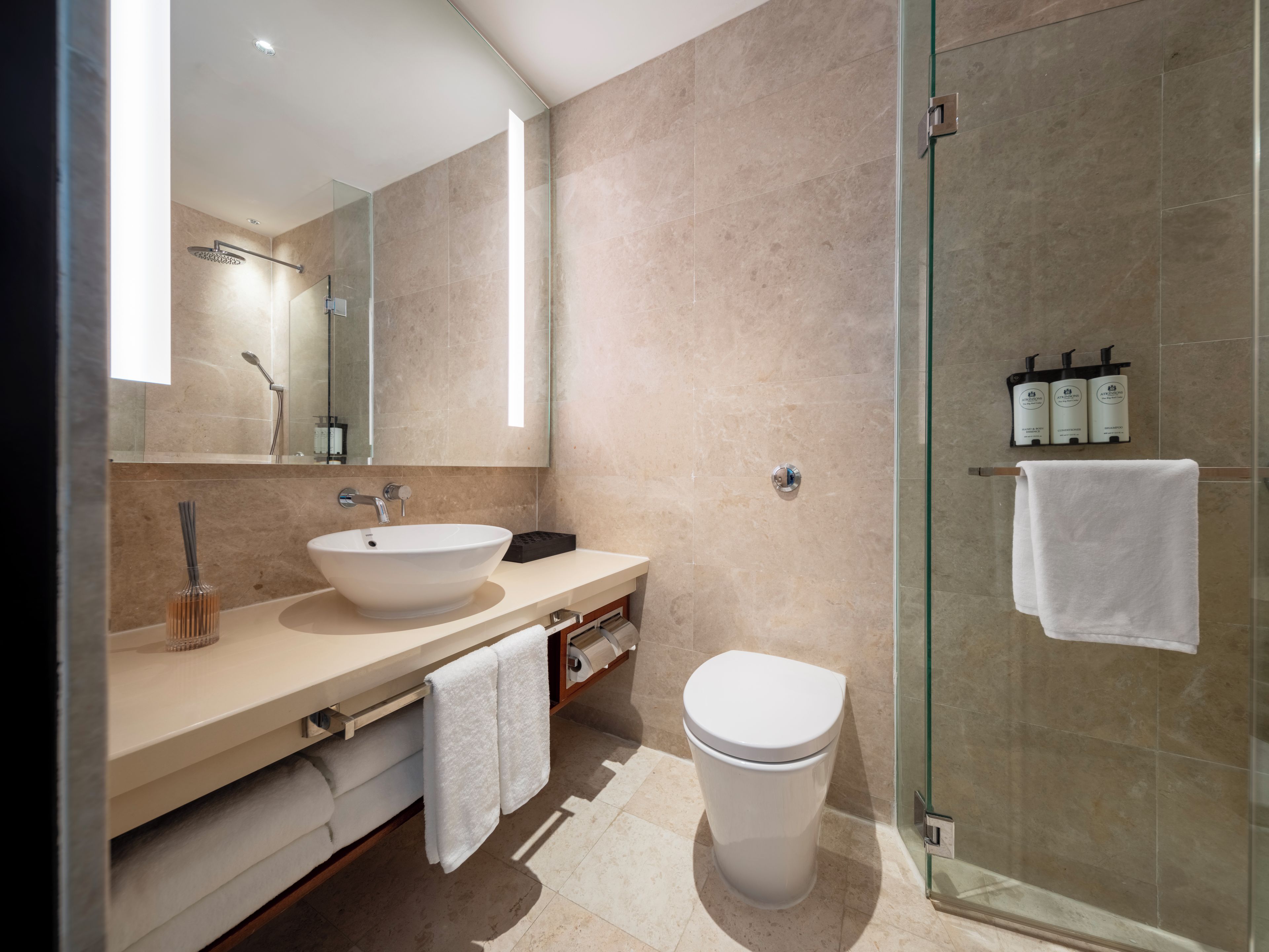 Un baño moderno con ducha acristalada, lavamanos amplio e inodoro.