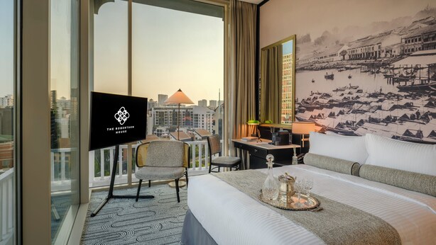 A hotel room with a large bed, a desk, a chair, a TV, and a city view through large windows. - Novotel Singapore Robertson Quay (Singapore)