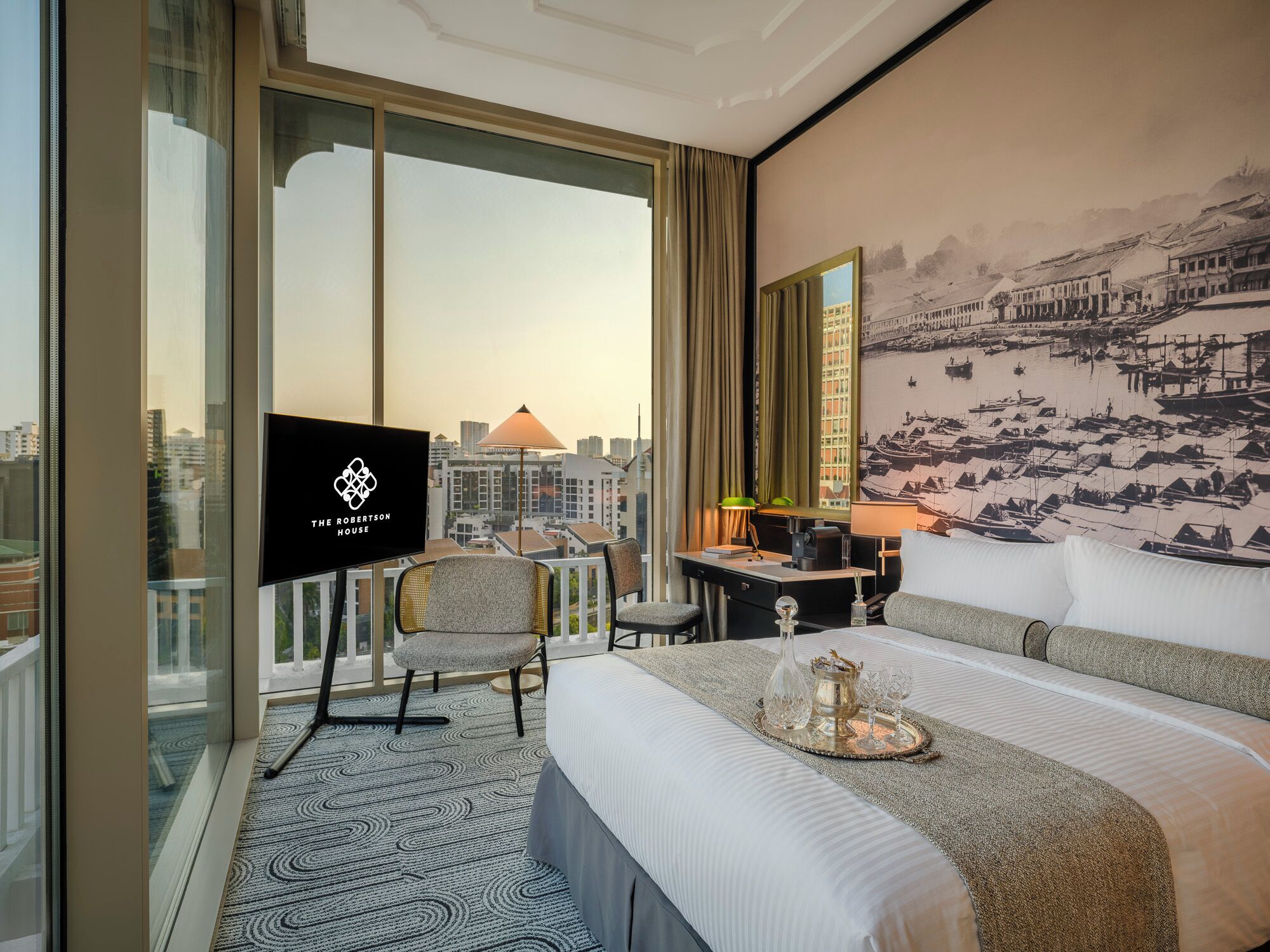 Habitación de hotel con una cama grande, un escritorio, una silla, un televisor y vistas a la ciudad.