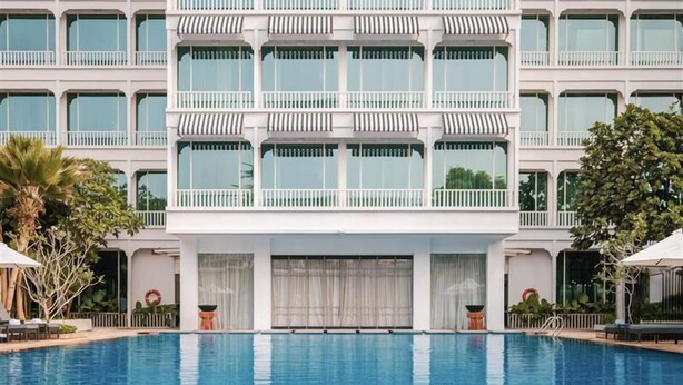 Un hotel moderno con una piscina grande al frente.