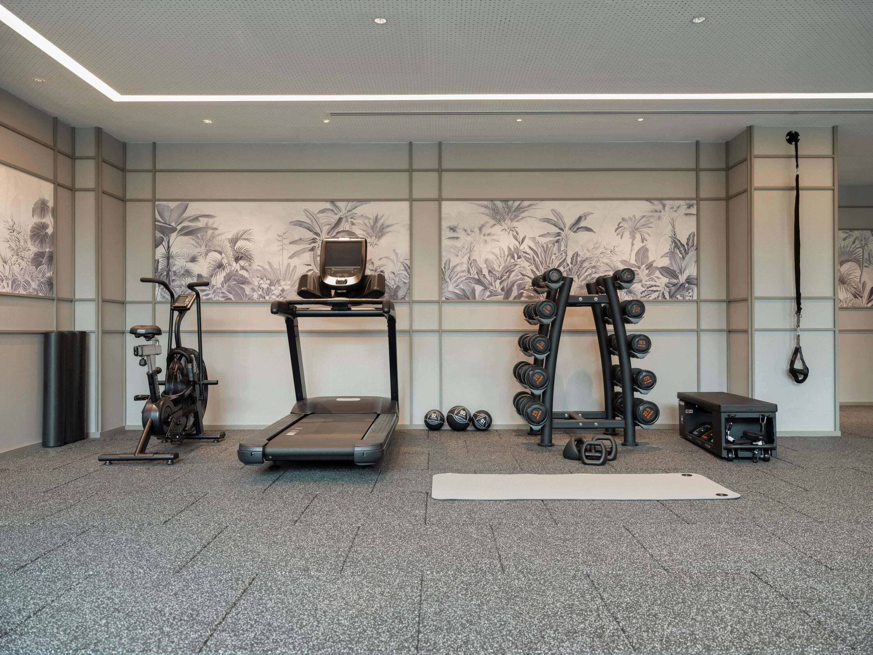 Une salle de sport équipée d’un tapis de course, d’un vélo d’exercice, d’haltères et d’un sac de frappe.