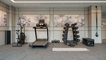 Une salle de sport équipée d’un tapis de course, d’un vélo d’exercice, d’haltères et d’un sac de frappe.