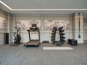 Un gimnasio con cinta de correr, bicicleta estática, mancuernas y un saco de boxeo.