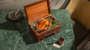 Un cofre de madera con un pollo asado sobre una mesa de mármol.