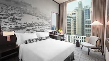 Habitación de hotel con una cama grande, un escritorio, una silla, vistas a la ciudad y una pared con una fotografía blanco y negro.