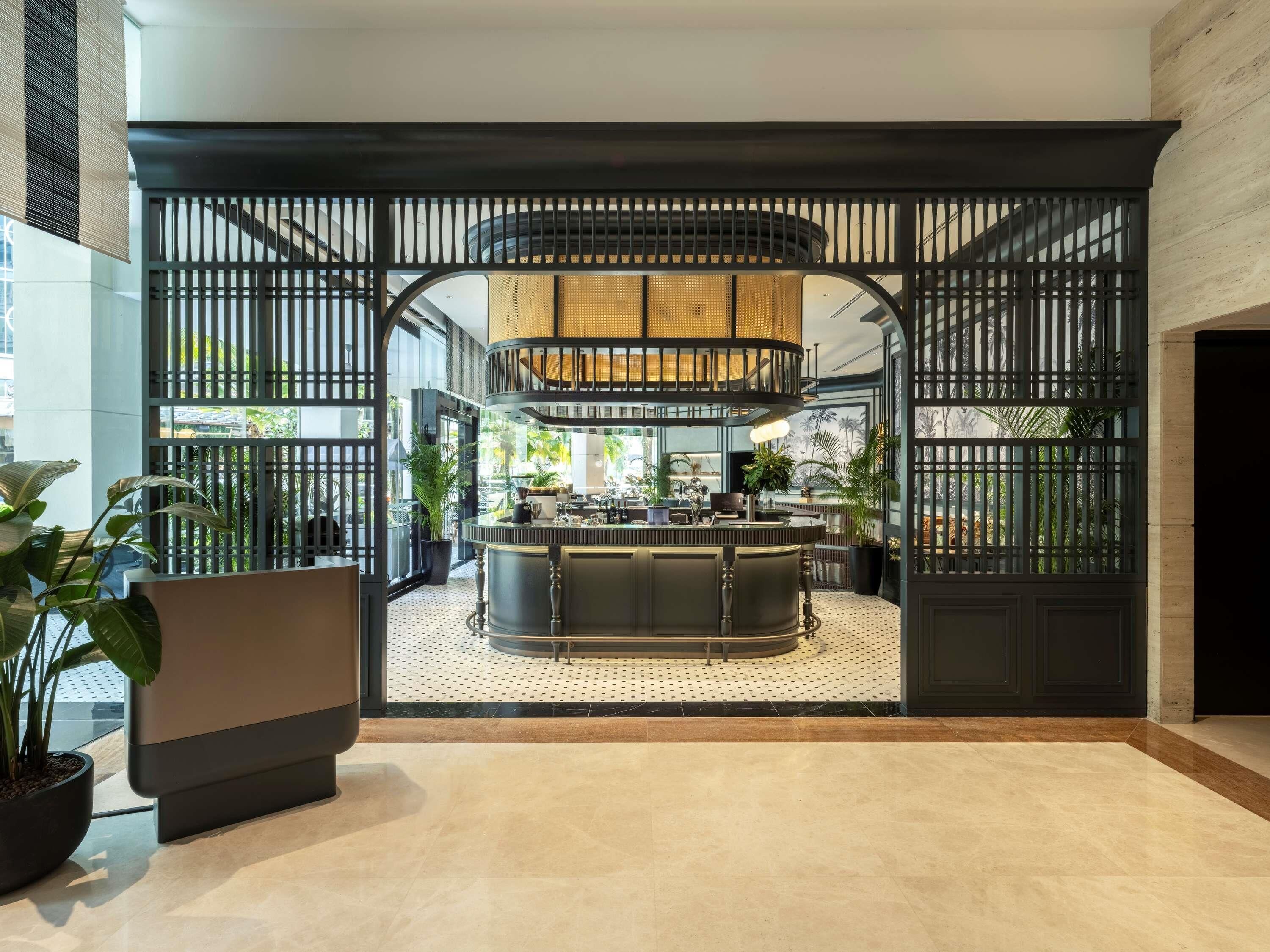 A modern interior with a central bar area, surrounded by a decorative black partition with vertical slats.