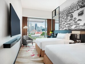 Habitación de hotel con vista a la ciudad, dos camas, un televisor, un escritorio y una silla.