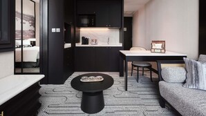 A modern hotel room with a kitchenette, a dining area with a table and chairs, a sofa, and a patterned rug. - Novotel Singapore Robertson Quay (Singapore)