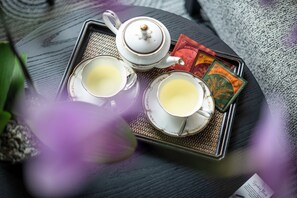 A tray with two cups of tea, a teapot, and some tea bags on a textured surface.
