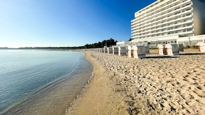 Un hotel frente a la playa con una extensa playa de arena y un cielo azul despejado.
