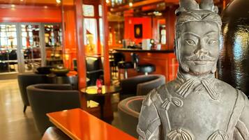 Eine Bar mit einer Statue, Sitzgelegenheiten und Flaschenregalen.