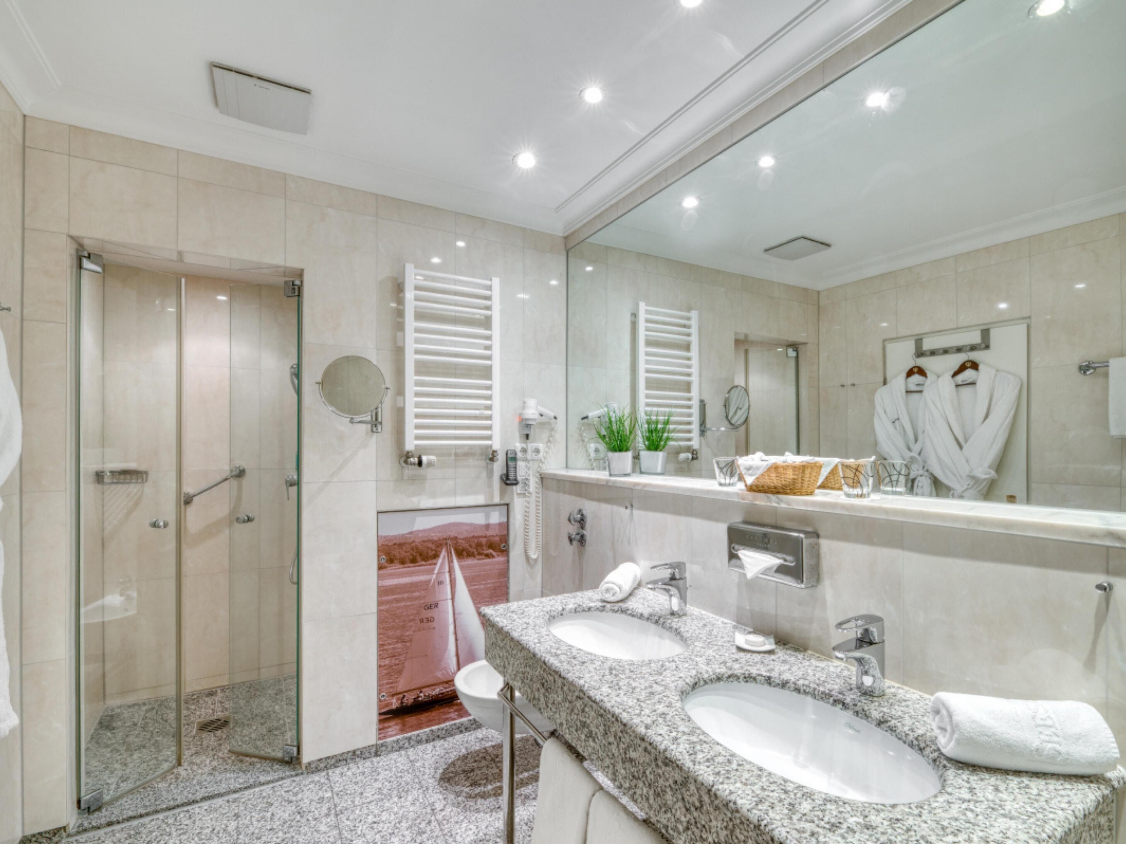 A modern bathroom with a glass shower enclosure, dual sinks, and a large mirror.