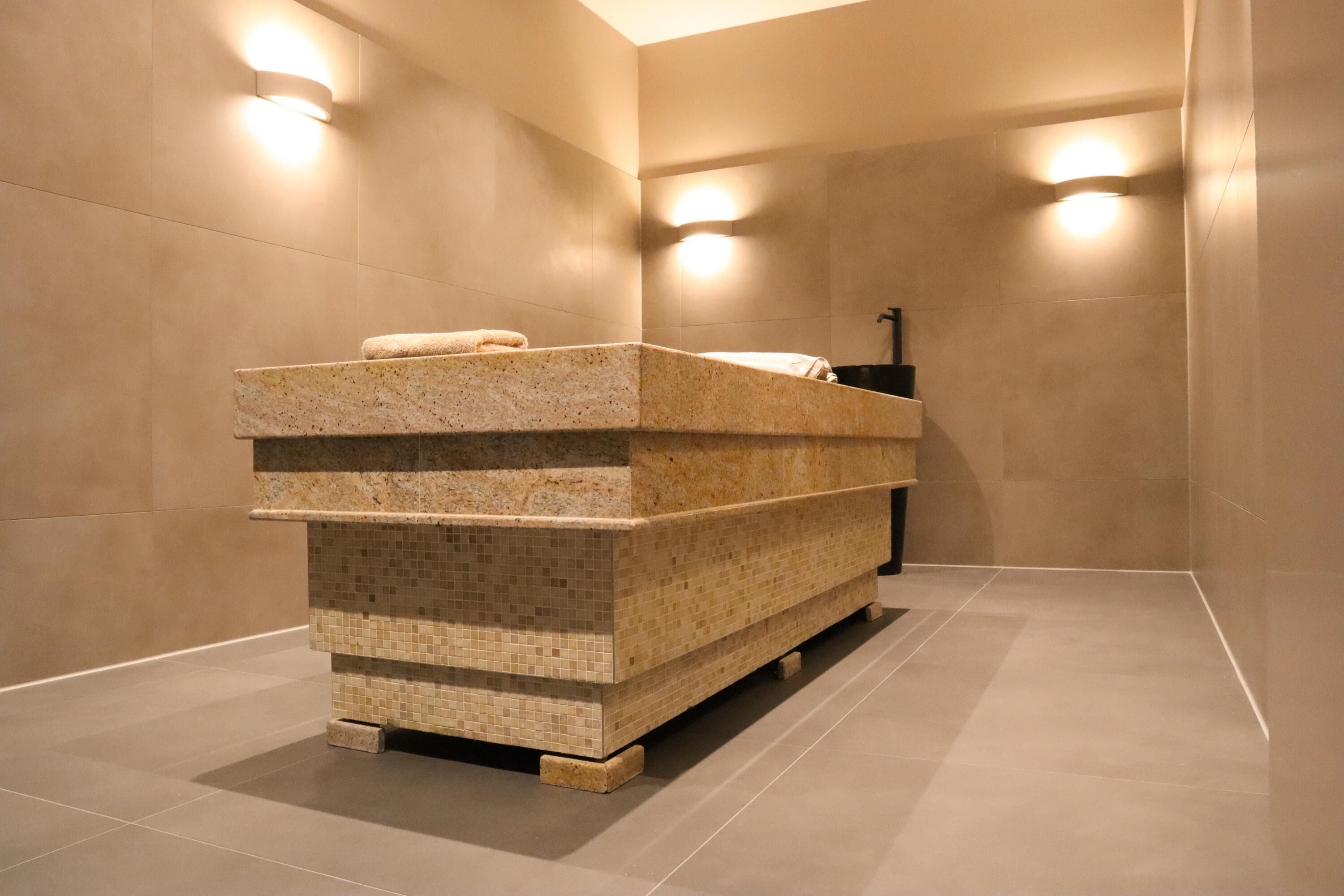 Un baño moderno con un lavamanos de granito independiente, paredes con azulejos e iluminación empotrada.
