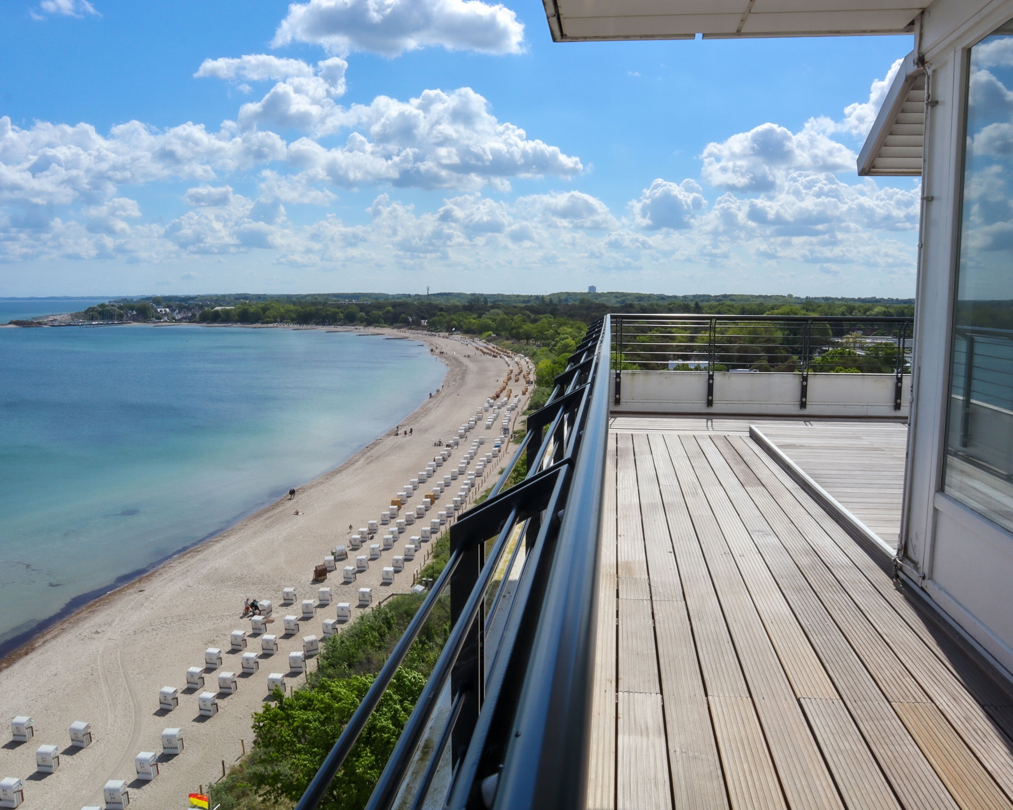 A wooden deck with a view of a beach and ocean.